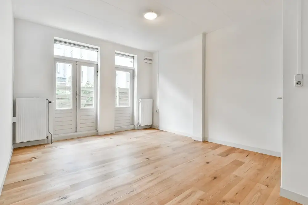 Estancia de un piso en Oviedo tras la reforma integral, con suelo de madera y paredes acabadas